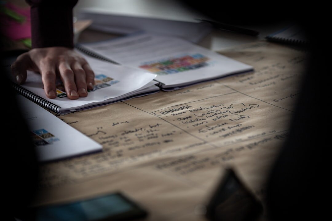 Journalist writing notes at a desk with newspapers